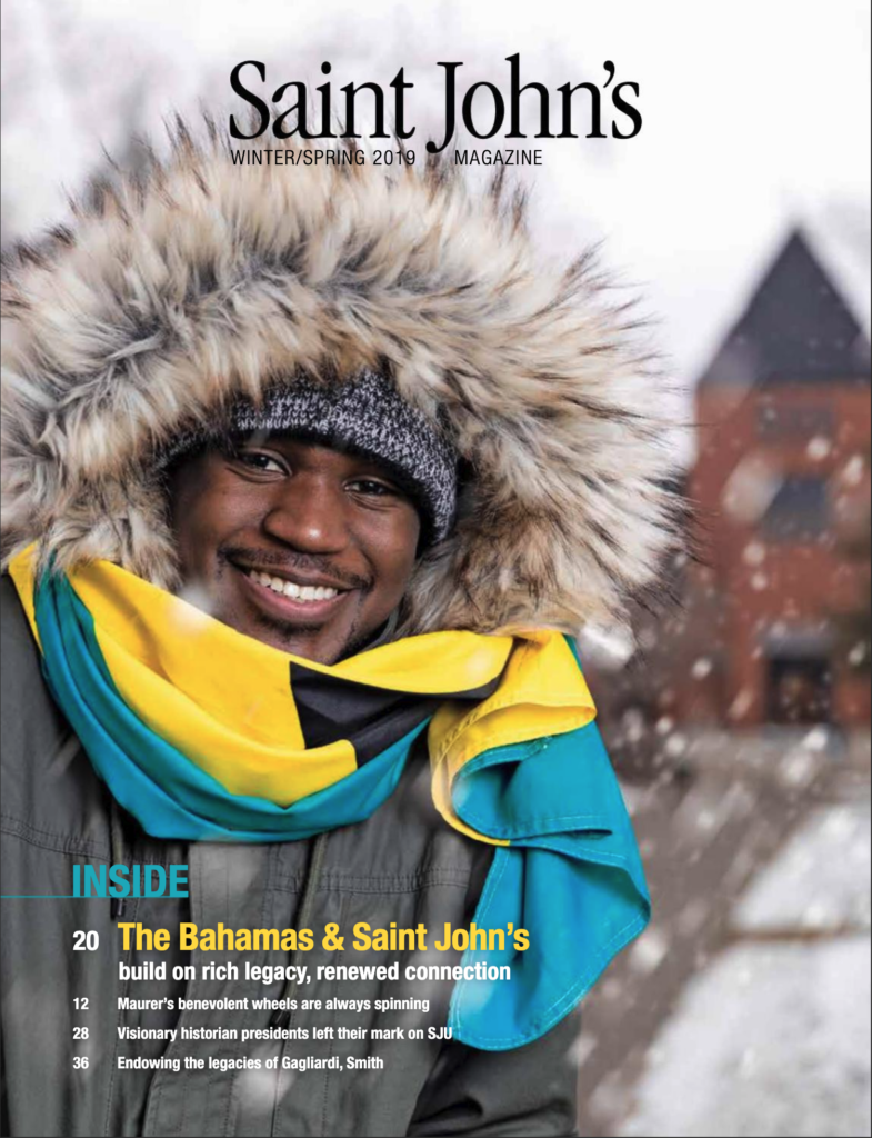 A smiling person stands outdoors in falling snow, wearing a fur-lined hooded coat and a colorful scarf. The person is in front of a blurred, snowy background. Text on the image includes "Saint John's Magazine" and article titles.